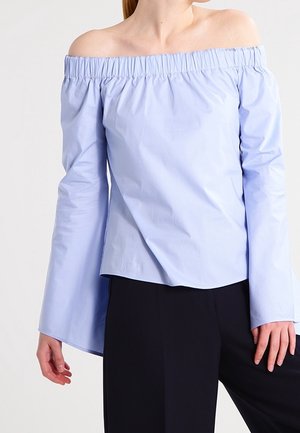 Light blue off-the-shoulder blouse with gathered neckline, long sleeves, and a relaxed fit; made of smooth fabric with slight sheen.