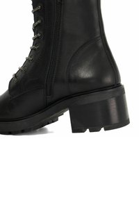 Bottine en cuir noir avec un solide talon bloc, un laçage à l'avant, des coutures décoratives et une fermeture éclair sur le côté pour un enfilage facile.