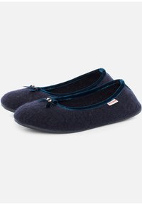 Pantofole in feltro blu navy con punta arrotondata, bordatura in velluto, piccolo fiocco decorativo e suola in gomma. Include un'etichetta con logo sul lato.