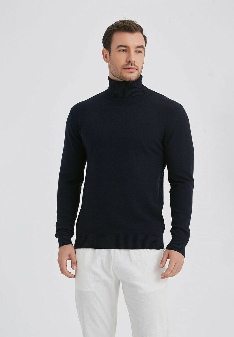 Pull ras du cou bleu marine en tissu tricoté doux. Design ajusté avec des poignets et un ourlet côtelés. Associé à un pantalon de couleur claire.