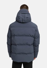 Vadderad, huva-jacka i mörkgrå, med en puffy design och vertikala sömmar samt hög krage. Tillverkad av ett slätt, väderbeständigt material.