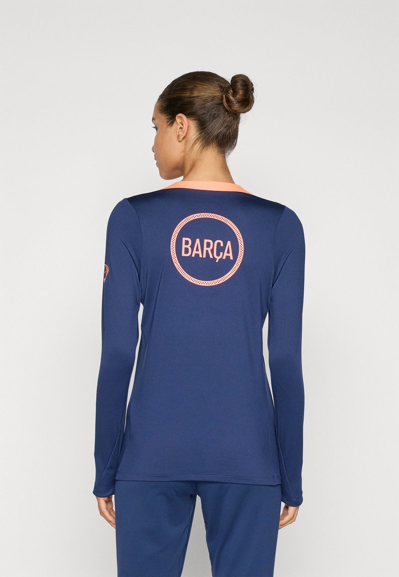 Marineblå langermet skjorte med rosa detaljer, med et sirkulært "BARÇA"-logo på baksiden. Glatt tekstur og atletisk passform.