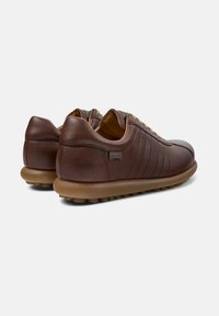 Pair of brown leather lace-up casual shoes with textured soles and branded side tag, shown from the back and side on white background.