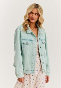Jasnozielona dżinsowa kurtka z dwoma przednimi kieszeniami, metalowymi guzikami i luźnym krojem. Posiada subtelne hafty na piersi.