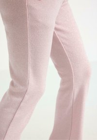 Rosa, ribbede bukser med en let glans. Har en flared form og lodrette linjer med subtile glimmerdetaljer i hele stoffet.