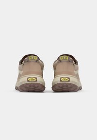 Beige utendørs joggesko med teksturert design, polstret hæl, gule "MTE" aksenter, og gummisåle. Har Vans-logo på sålen.