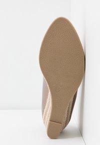 Scarpa con tacco marrone con suola testurizzata, caratterizzata da un accento in tessuto intrecciato. Taglia 37 riportata sul fondo. Finitura liscia sulla parte superiore.