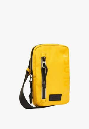 Gul crossbody taske lavet af slidstærkt stof, med et hovedrum med lynlås, frontlomme med lynlås og en skulderrem med justerbar længde.
