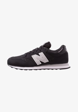 Czarny but sportowy New Balance z białym logo, czarnymi sznurowadłami i białą podeszwą, pokazany z boku na białym tle.