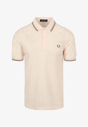 Polo de tela rosa claro con cuello clásico, tapeta de dos botones y acentos de rayas marrones en el cuello y las mangas. Logo en el pecho.