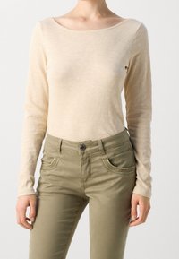 Beige top met lange mouwen van lichtgewicht stof, ronde halslijn, gecombineerd met olijfgroene broek met decoratieve stiksels en steekzakken aan de voorkant.