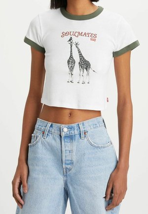 Biały skrócony T-shirt z zielonym wykończeniem, z grafiką żyrafy i napisem "SOULMATES" w kolorze czerwonym. W połączeniu z jasnoniebieskimi dżinsami.