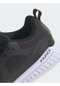 Black athletic shoe with a textured mesh upper, gray accents, a white sole, and "bounce" branding on the side. Features a looped heel tab.