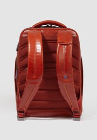 Rode leren rugzak met een gewatteerde, textuurrijke achterkant, verstelbare schouderbanden en blauwe ritsaccenten. Heeft een gestroomlijnd ontwerp.