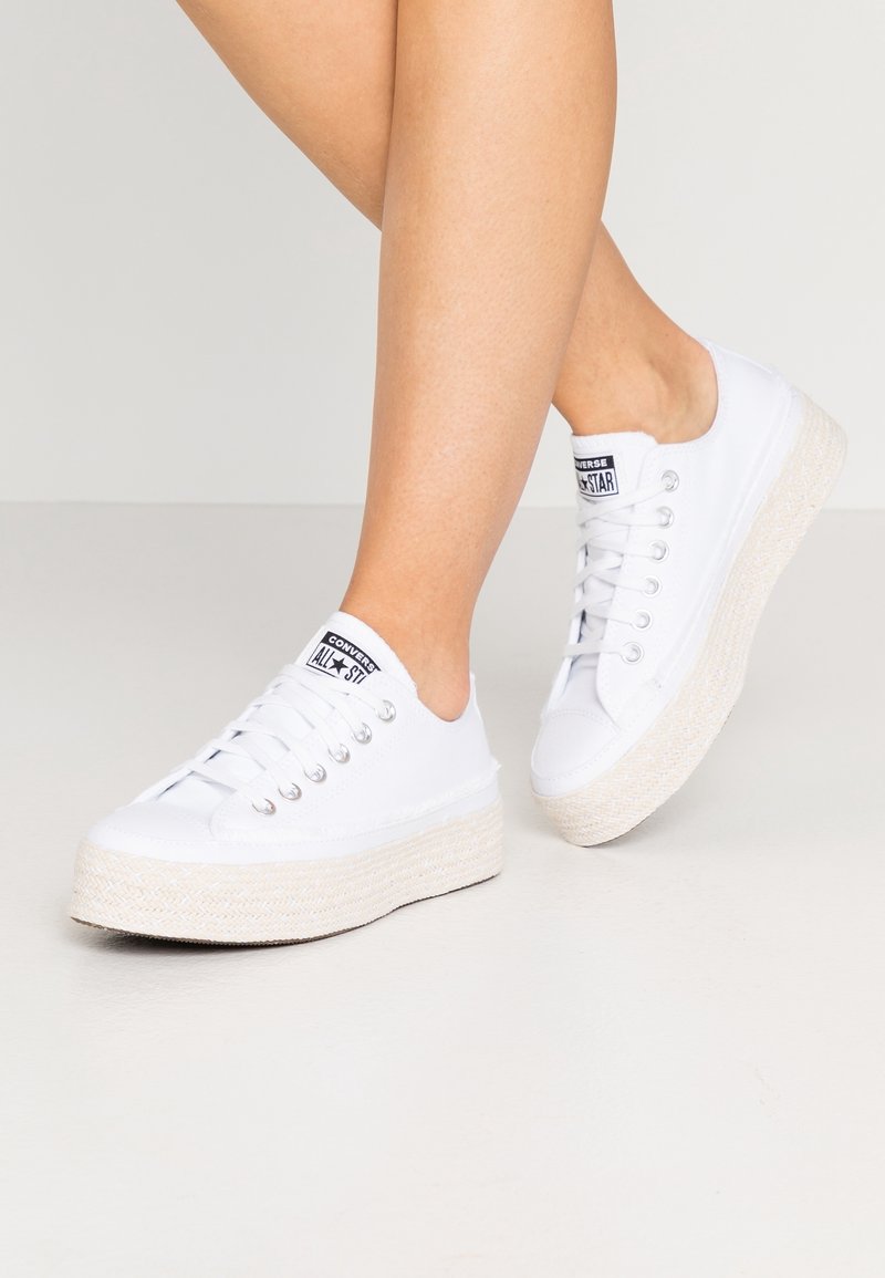 Sneakers bianchi in tela con una suola platform in fibra naturale testurizzata. Presentano un classico design con lacci e un'etichetta nera con logo sulla linguetta.
