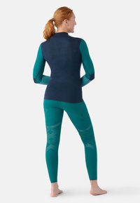 Navy and teal athletic set featuring a long-sleeve top and fitted leggings, with textured patterns on the leggings and contrast sleeves.