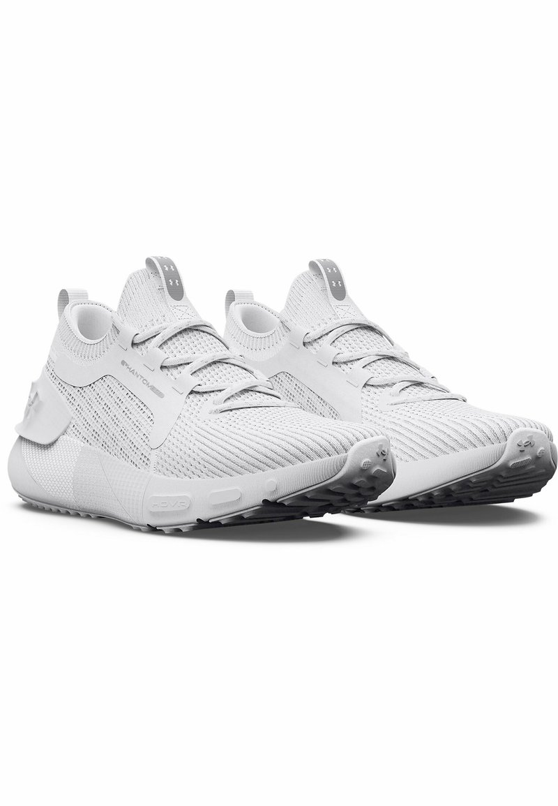 Un par de zapatillas deportivas blancas con parte superior de punto, cordones, suelas acolchadas y etiquetas de marca en la lengüeta y el talón, vista lateral en ángulo.