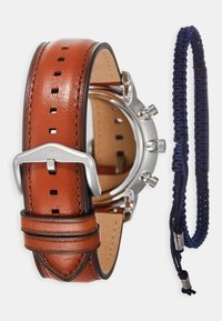 Fossil-Uhr mit einem braunen Lederarmband mit quadratischen Löchern und einer silbernen Metallschließe. Enthält ein blaues Paracord-Armband.