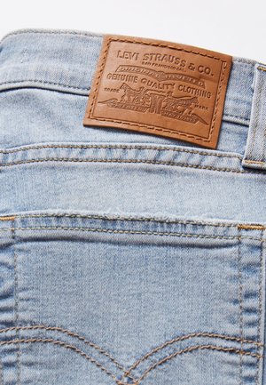 Lichtblauwe spijkerbroek van denim met een bruin leren Levi Strauss & Co.-label boven de achterzak genaaid.