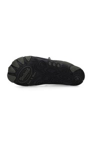 Black rubber shoe sole with textured patterns and raised accents, featuring circular and oval designs with "Dockers" logo clearly visible.