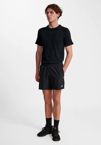 Schwarzes Sport-T-Shirt mit kurzen Ärmeln, kombiniert mit schwarzen Shorts mit elastischem Bund und kleinem Logo am Bein.