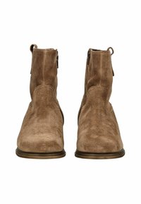Une paire de bottines en daim marron avec des zips latéraux, des bouts ronds et des languettes à l'arrière, présentées de face sur un fond blanc.