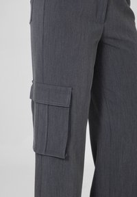 Pantaloni cargo grigi scuri con tessuto testurizzato, caratterizzati da una tasca laterale con pattina e dettagli cuciti. Adatti in vita, con una vestibilità ampia.