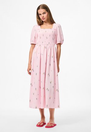 Light pink midi dress made of textured fabric, featuring a square neckline, puff sleeves, and floral embroidery; paired with pink flip-flops.