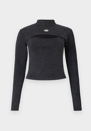 Top corto negro de manga larga con cuello alto, detalle recortado en el pecho y un pequeño logo metálico ovalado en la parte superior del pecho.
