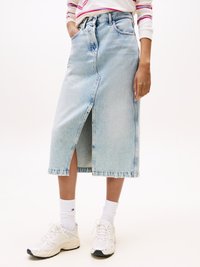 Svetlo modra jeans krila z odprtinami spredaj, ki ima dve stranski žepi in visok pas. V kombinaciji z belimi športnimi copati in nogavicami.
