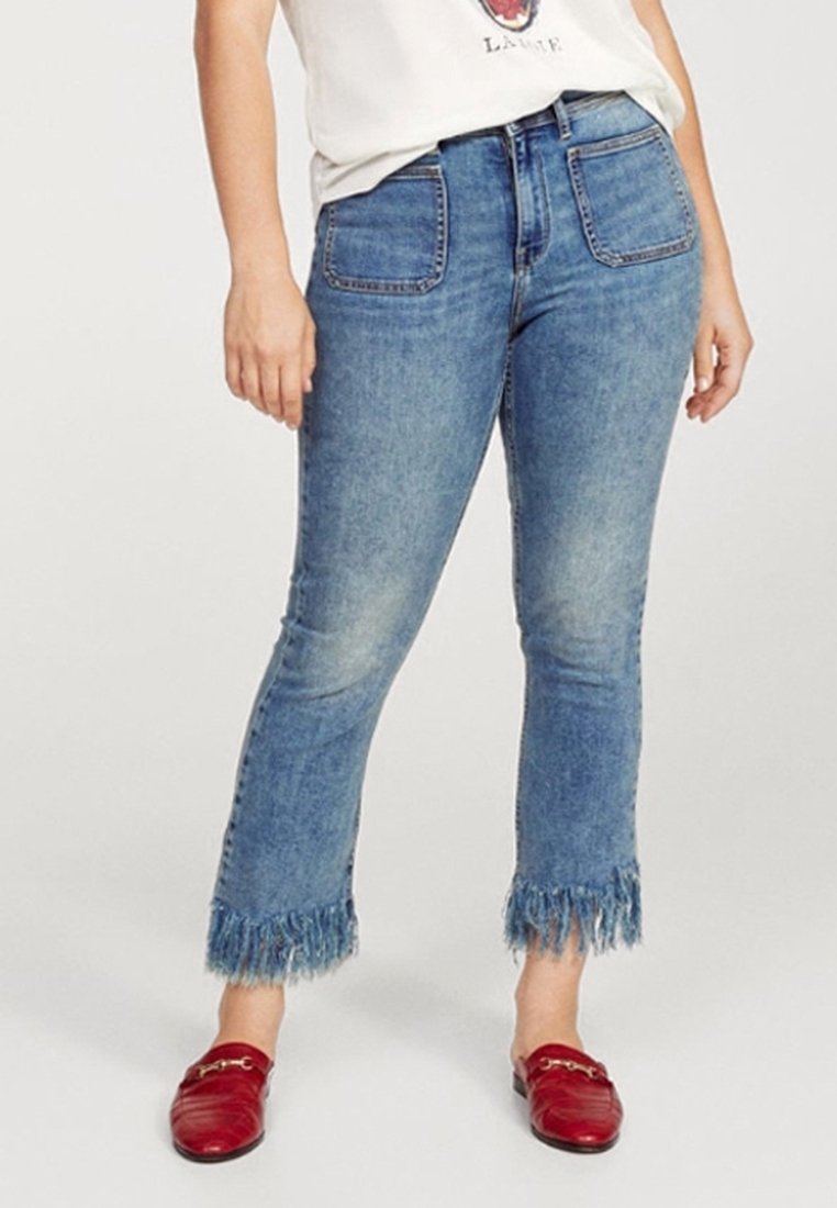 Jeans in denim blu chiaro con orlo sfilacciato, due tasche frontali e due tasche posteriori; abbinati a mocassini rossi.