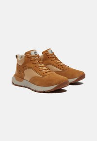 Le scarpe da trekking alte in suede marrone e rete presentano un design alto, suole in gomma e una leggera personalizzazione sulla linguetta e sul lato. Inclusi dettagli di colore chiaro.