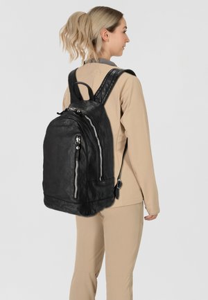 Zaino in pelle nera con cerniere argento, spallacci regolabili imbottiti e maniglia superiore. Presenta una superficie liscia e un design minimalista.