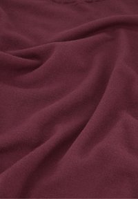 Bordeaux stof met een zachte, gestructureerde oppervlakte, voorzien van een ronde hals en gedrapeerde plooien. Geschikt voor casual wear en lagen.
