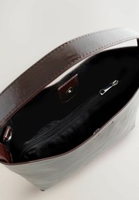 Hallhalli hallnahk (hall nahk) kott, millel on läikiv pruun rihm, sisemine tõmblukk-tasku ja sile tekstuur. Üks avatud ülaosa disain, minimaalsed metalldetailid.