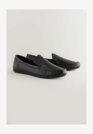 Čierne kožené mokasíny s textúrou v podobe krokodílej embossácie. Majú nízky profil, štýl na jednoduché obuť a viditeľné švy ako dekoratívne prvky.