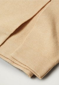 Beige Textil gefaltet, strukturierter Strick mit sichtbaren Rippenmustern. Glatte Oberfläche mit leichtem Glanz, die das weiche und leichte Material zur Geltung bringt.
