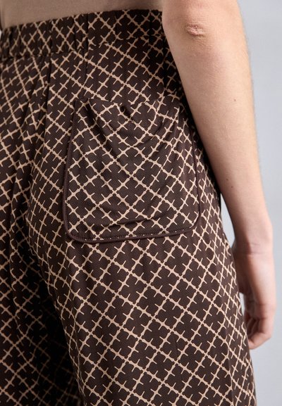 Brune mønstrede bukser med et geometrisk design i beige, med en baglomme udformet med en kontrasterende kant. Blød tekstur og afslappet pasform.