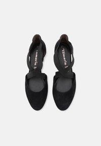 Czarne zamszowe baleriny z krzyżującymi się elastycznymi paskami na podbiciu, zaokrąglonym noskiem i wkładką z materiału imitującego skórę. Minimalistyczny design, brak widocznego logo.
