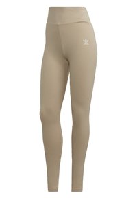 Beige High-Waist Leggings von Adidas mit weißem Trefoil-Logo am oberen linken Oberschenkel, schlanker Schnitt und knöchellange Ausführung.