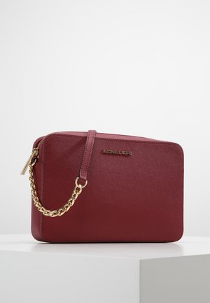 Bordeauxrode leren Michael Kors clutch met gouden kettingriem en rits, rechthoekige vorm, tentoongesteld op een wit voetstuk.