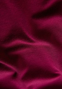 Glat, dyb burgunderstof med subtil tekstur og bløde folder, der fremhæver dets fine strikkede materiale.