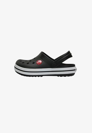 Des Crocs noirs avec un design à enfiler, comportant des trous de ventilation, des rayures blanches sur la semelle et un détail de logo rouge.