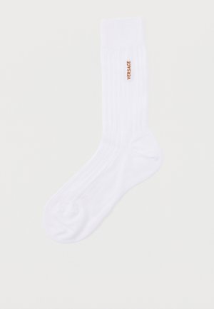 Weißer halbhoher Socken mit gerippter Textur und kleinem goldfarbenem "VERSACE"-Schriftzug an der Seite.