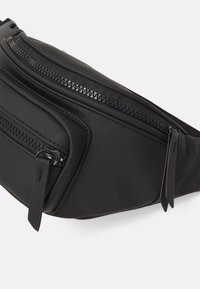 Banane en nylon noir avec deux compartiments horizontaux zippés, texture lisse et design minimaliste. Dotée de sangles plates pour un port sécurisé.