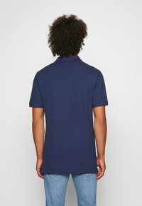 Polo shirt blu navy in cotone con colletto, maniche corte e orlo dritto. La texture appare liscia senza motivi o dettagli visibili.