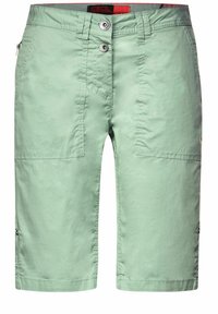 Shorts vert clair avec une texture lisse, deux grandes poches avant, fermeture à bouton et une poche latérale zippée. Tissu durable.