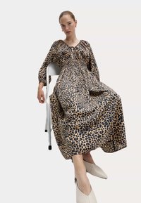 Šaty s leopardím potiskem z lehkého materiálu, s nařaseným korzetem, dlouhými rukávy a plnou sukní. V kombinaci s bežovými špičatými balerínami.