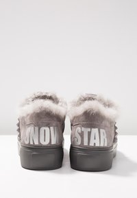 Paire de baskets en daim gris avec colliers duveteux, semelles épaisses noires, et les mots "SNOW" et "STAR" imprimés en grandes lettres blanches sur les talons.