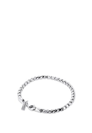 Bracelet chaîne boîte en argent avec fermoir mousqueton et petite étiquette rectangulaire près du fermoir sur fond blanc.